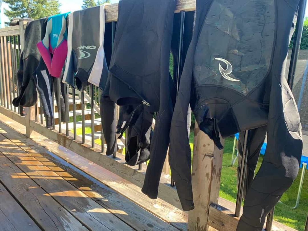 wetsuits hanging over rail drying