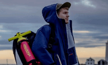 man in dryrobe with inflatable SUP on back