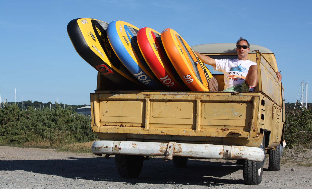 man with SUP boards sitting on back of van